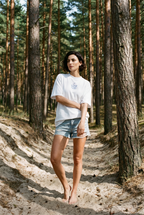 Model trägt HALO Statement T-Shirt Klappstuhl White Pearl im Kiefernwald an der Ostsee